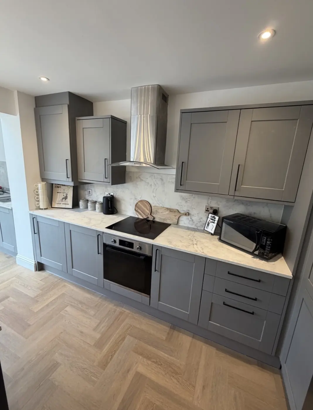 Grey shaker kitchen units with marble-effect quartz worktop and splashback