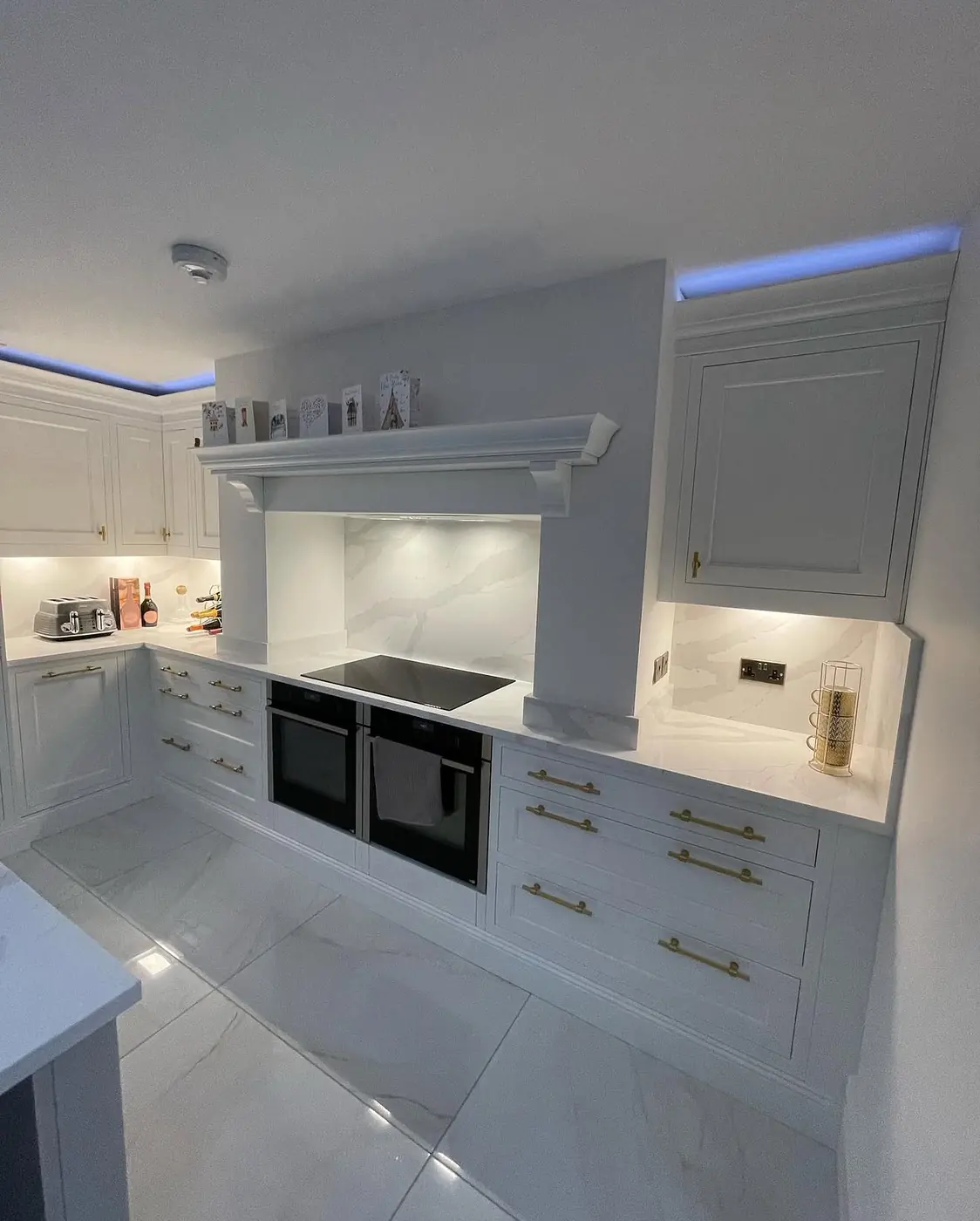 White in-frame style kitchen with mantle canopy and LED plinth lighting