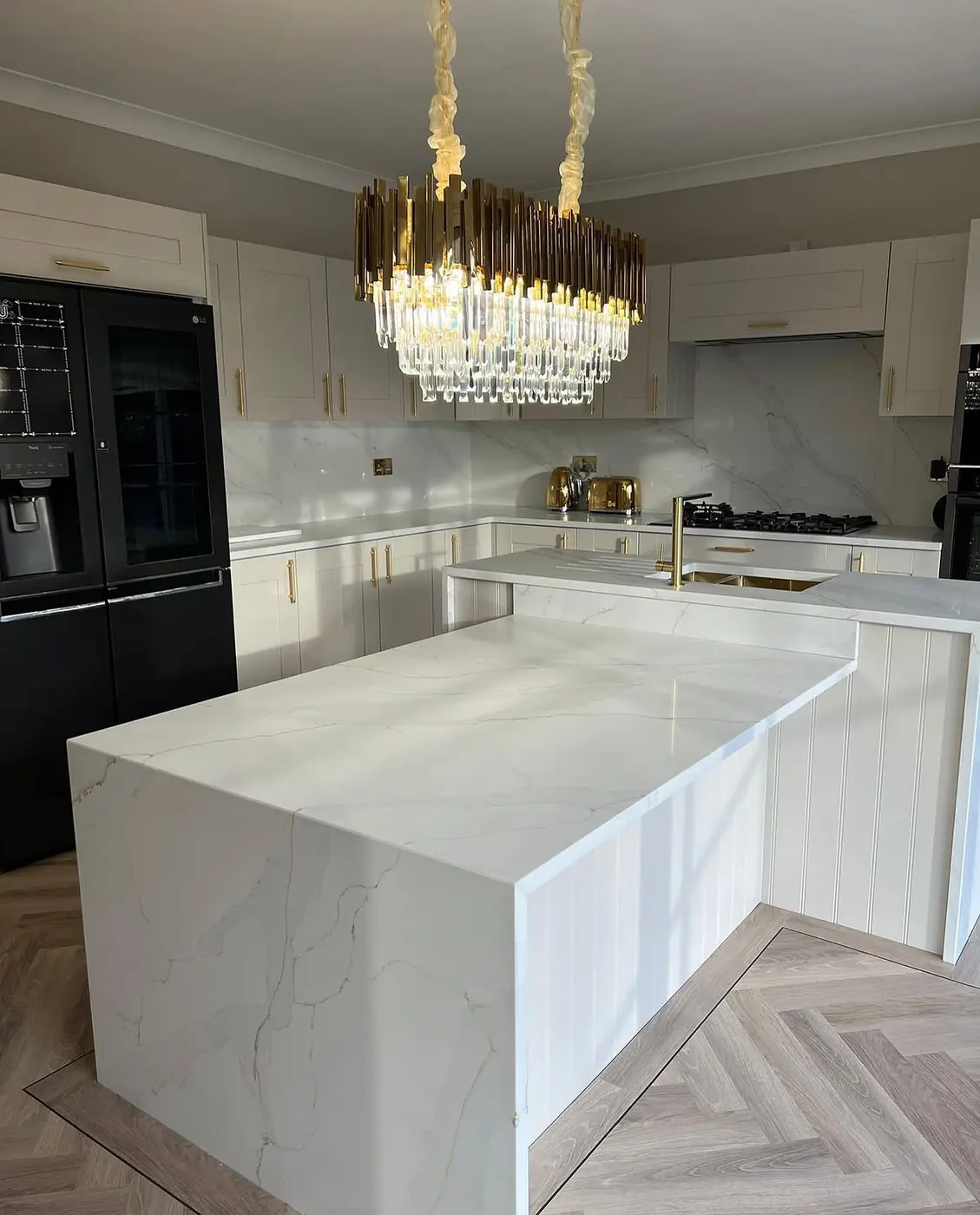 Waterfall-edge island beneath a crystal chandelier